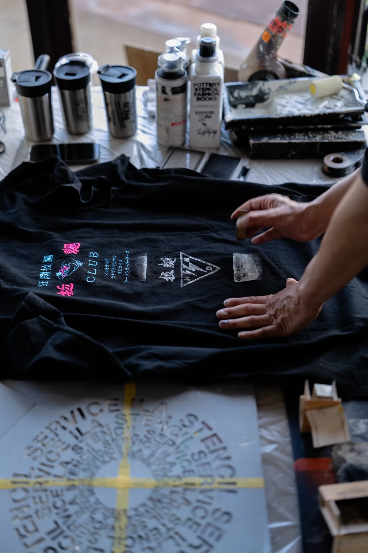 持ち込みの黒いTシャツにステンシルを施す手元